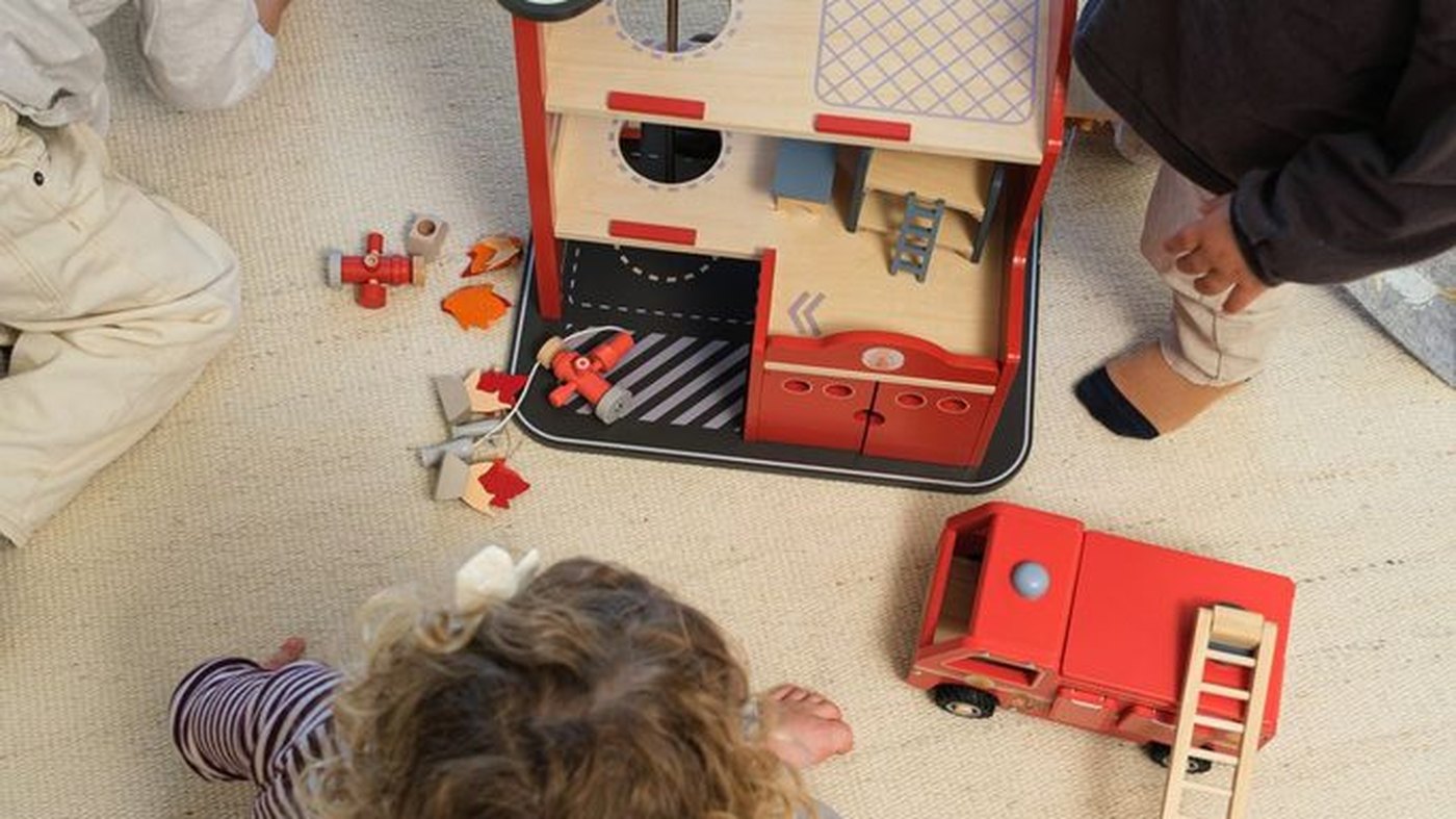 Two children playing with the large wooden fire station