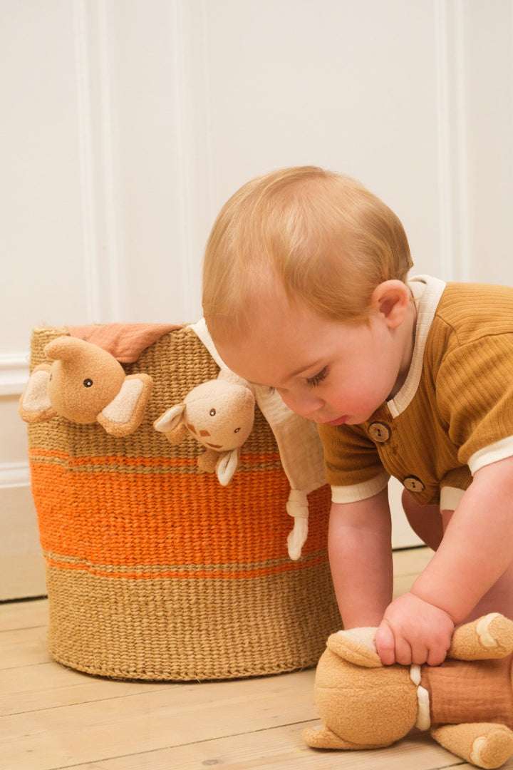 Baby playing with Ollie elephant doudou in basket
