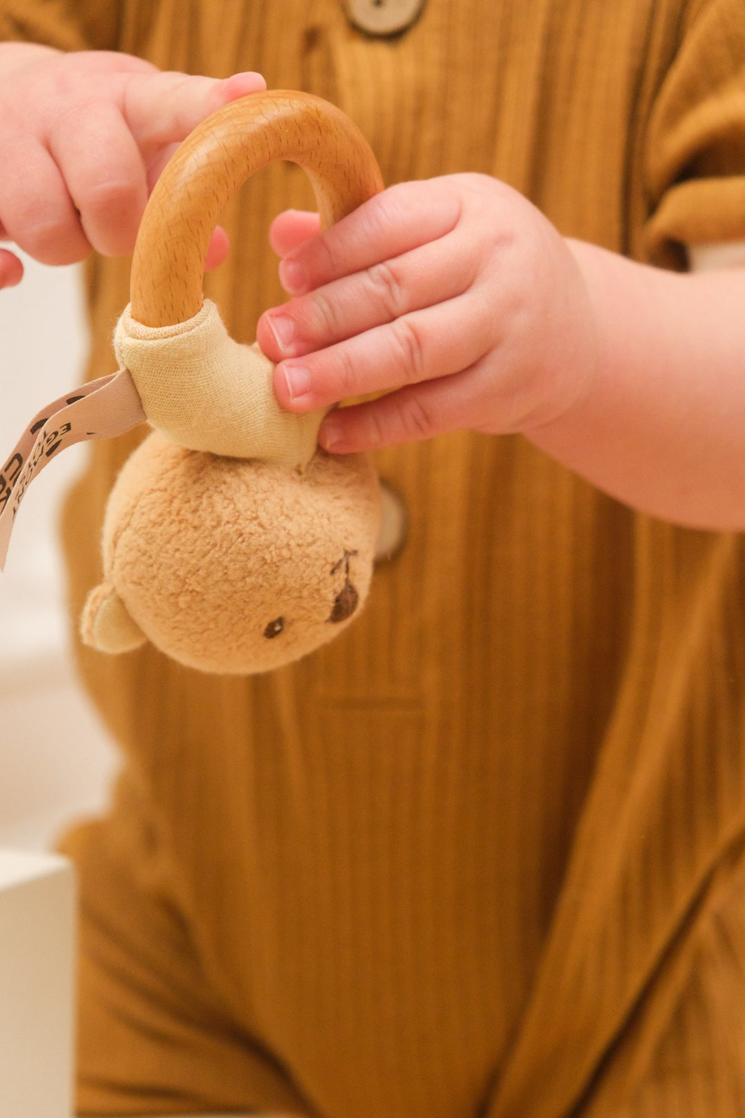Baby hands exploring Marcel bear wooden rattle