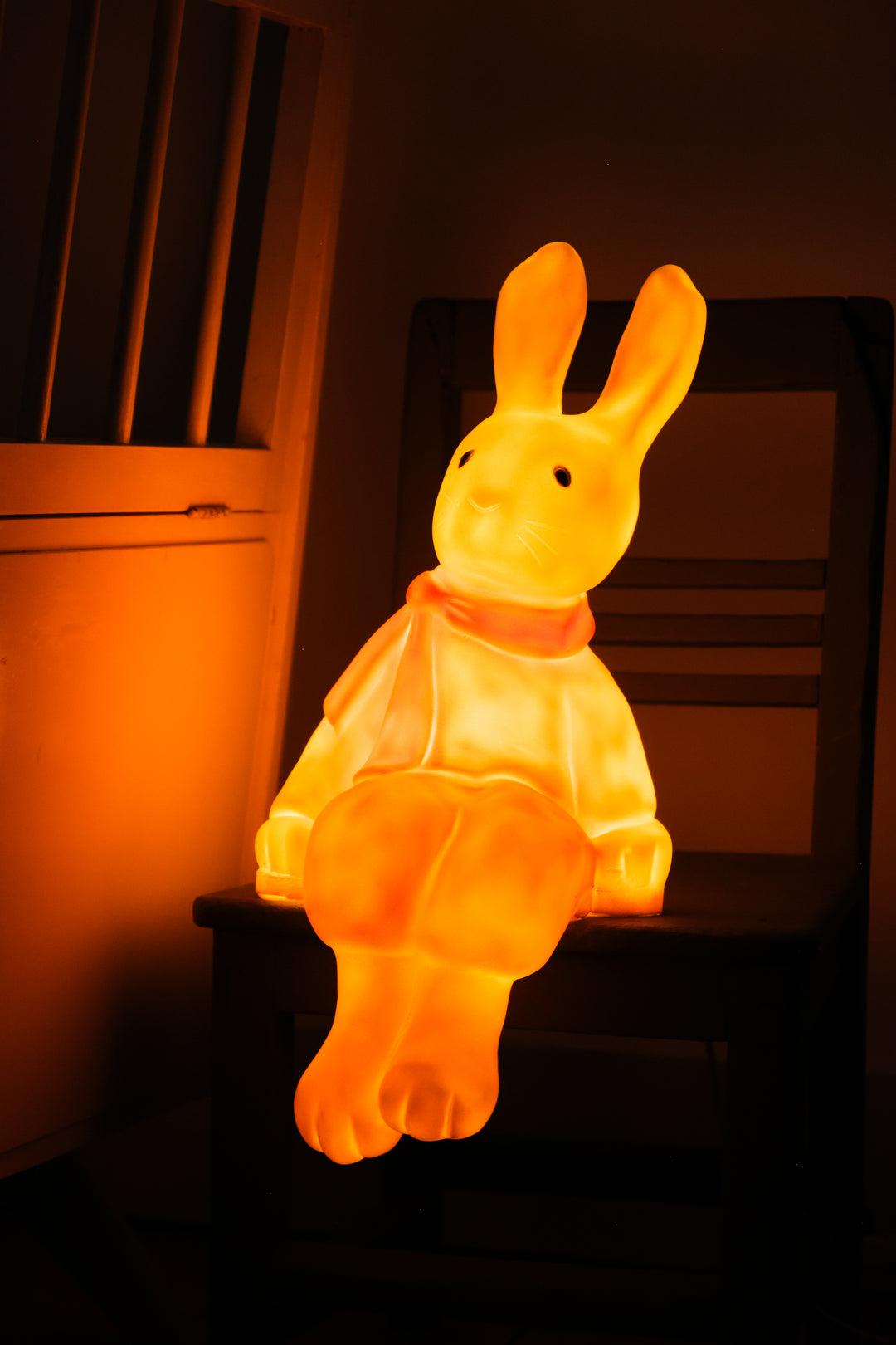 Lenny the Rabbit night lamp lit on a wooden chair at bedtime