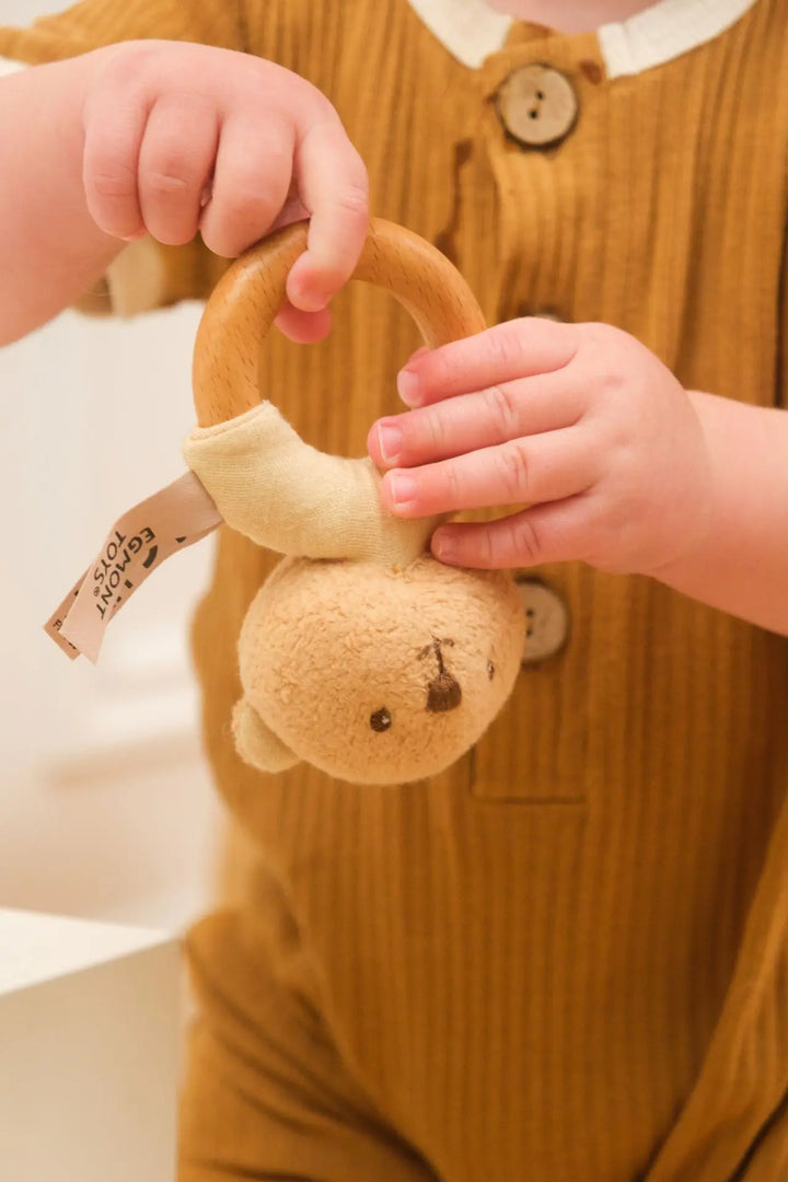 Baby hands exploring Marcel bear wooden rattle (close-up)
