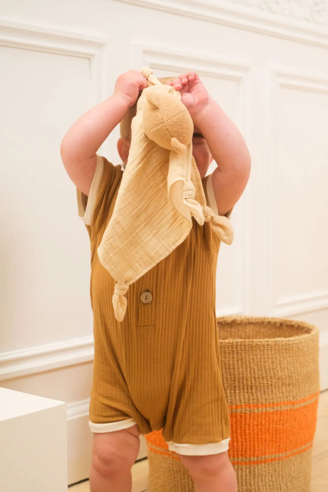 Baby lifting Marcel bear doudou overhead