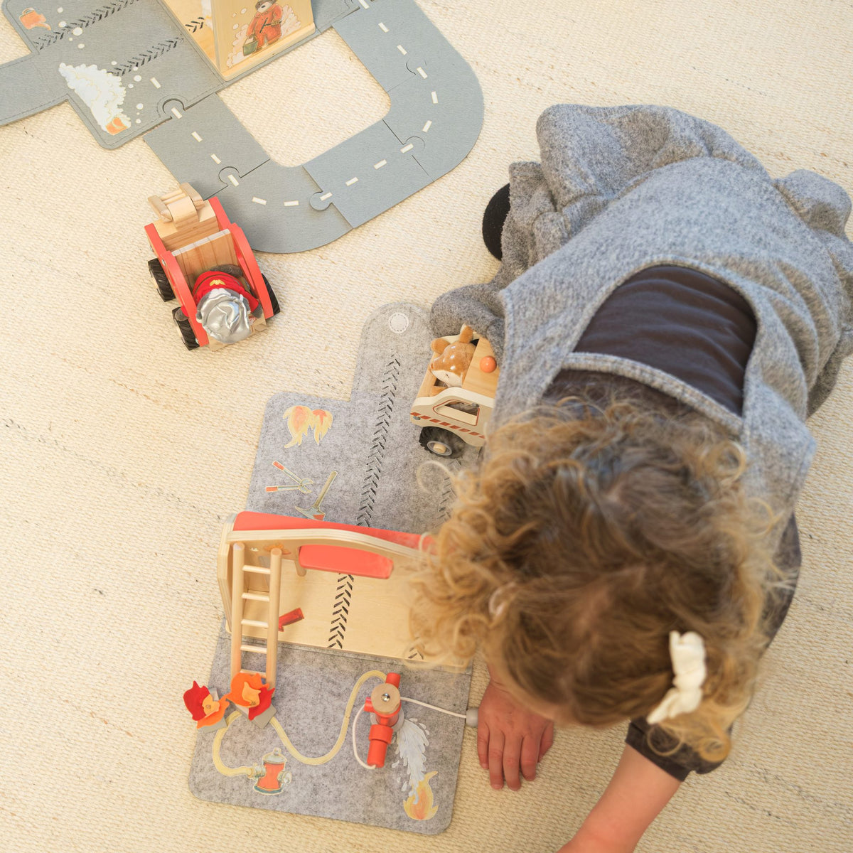 A child playing with the rescue vehicles on the felt play mats